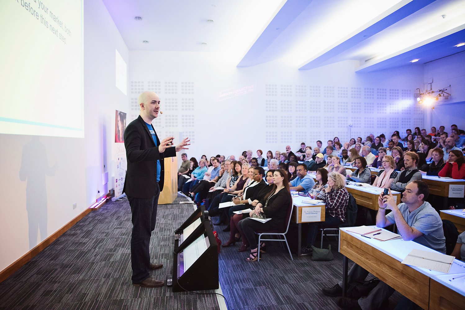 Owner of Upscale Ads, Matt Duggan, on stage at Shaa Wasmund's bootcamp, speaking to a full audience about Facebook and Instagram Ads.